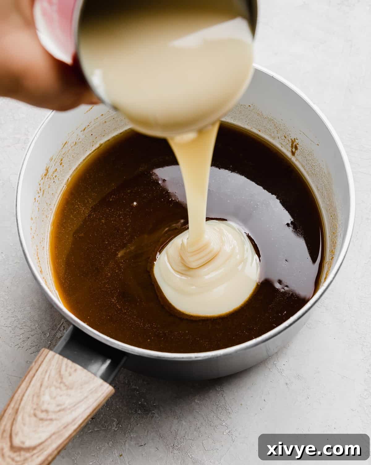 Decadent Banoffee Pie with Crunchy Graham Crust 6 Sweetened condensed milk being poured into a saucepan that has a dark brown sugar mixture melted.