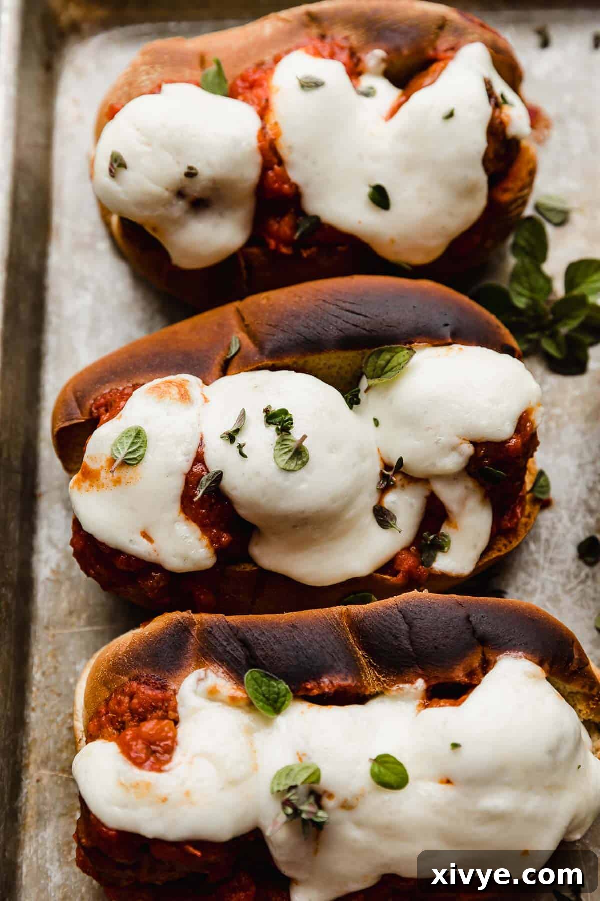 Saucy Italian Meatball Heroes 6 Melted mozzarella cheese overtop of Italian Meatball Subs on a baking sheet.