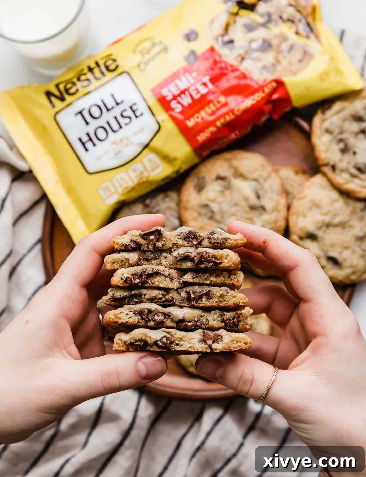A hand holding a stack of chocolate chip nestle toll house cookies that have been cut in half.