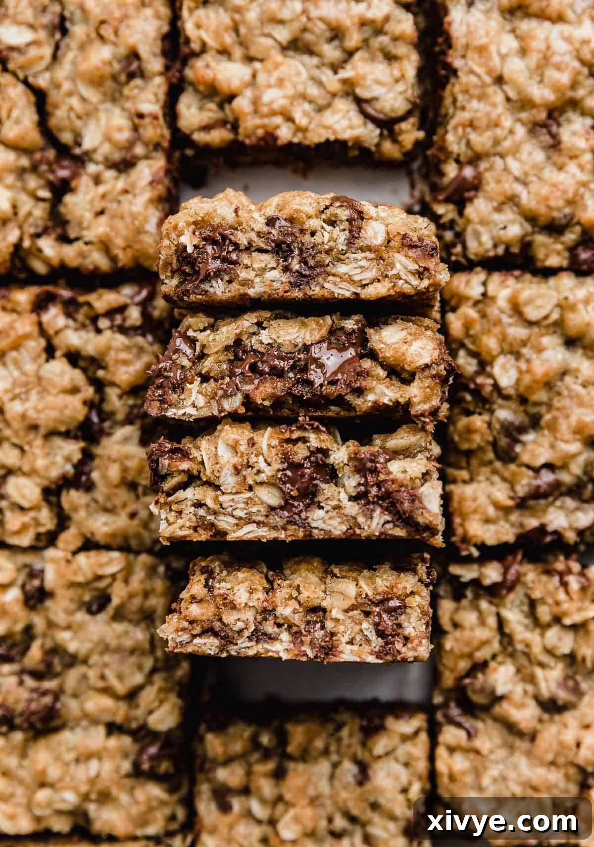 Four Brown Butter Chocolate Chip Oatmeal Cookie Bars perfectly balanced on their edges, offering a tantalizing view of their chewy interior and abundant chocolate chips. 