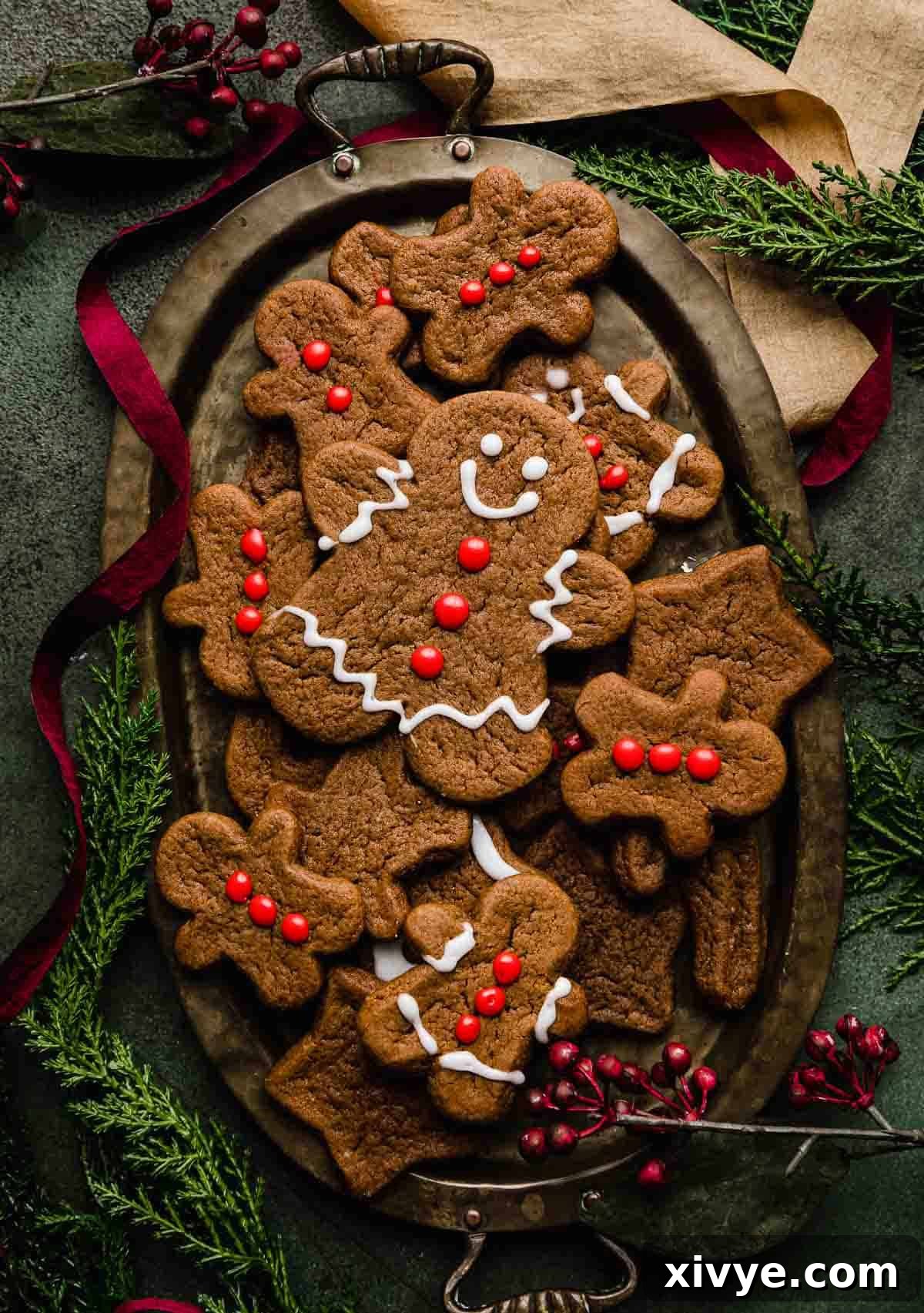 Soft Gingerbread Cookies on an oval plate on a dark green background with red and gold ribbon swirling around the plate.