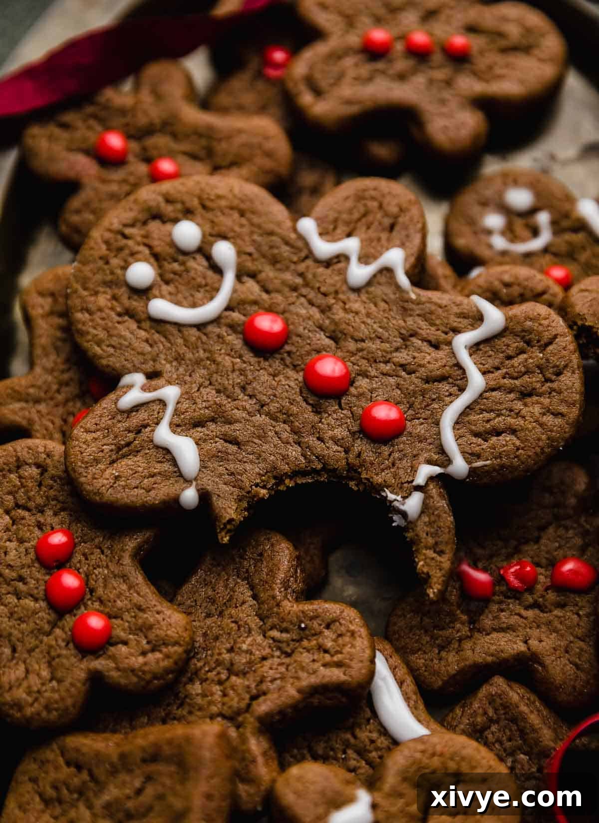A gingerbread man cookie decorated with white frosting and red frosting buttons.