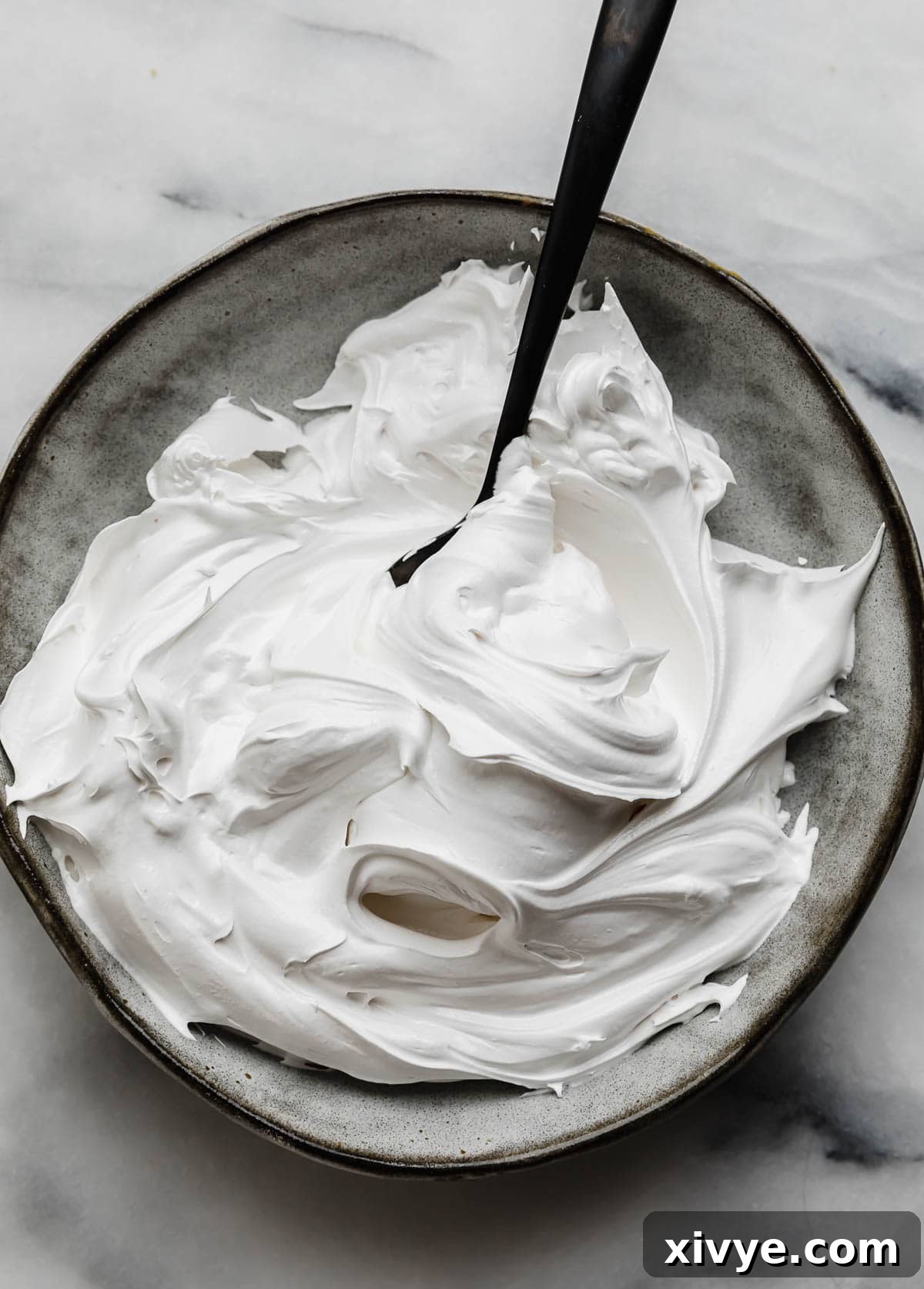 Homemade Marshmallow Cream fluffed into swirls on a gray plate. 
