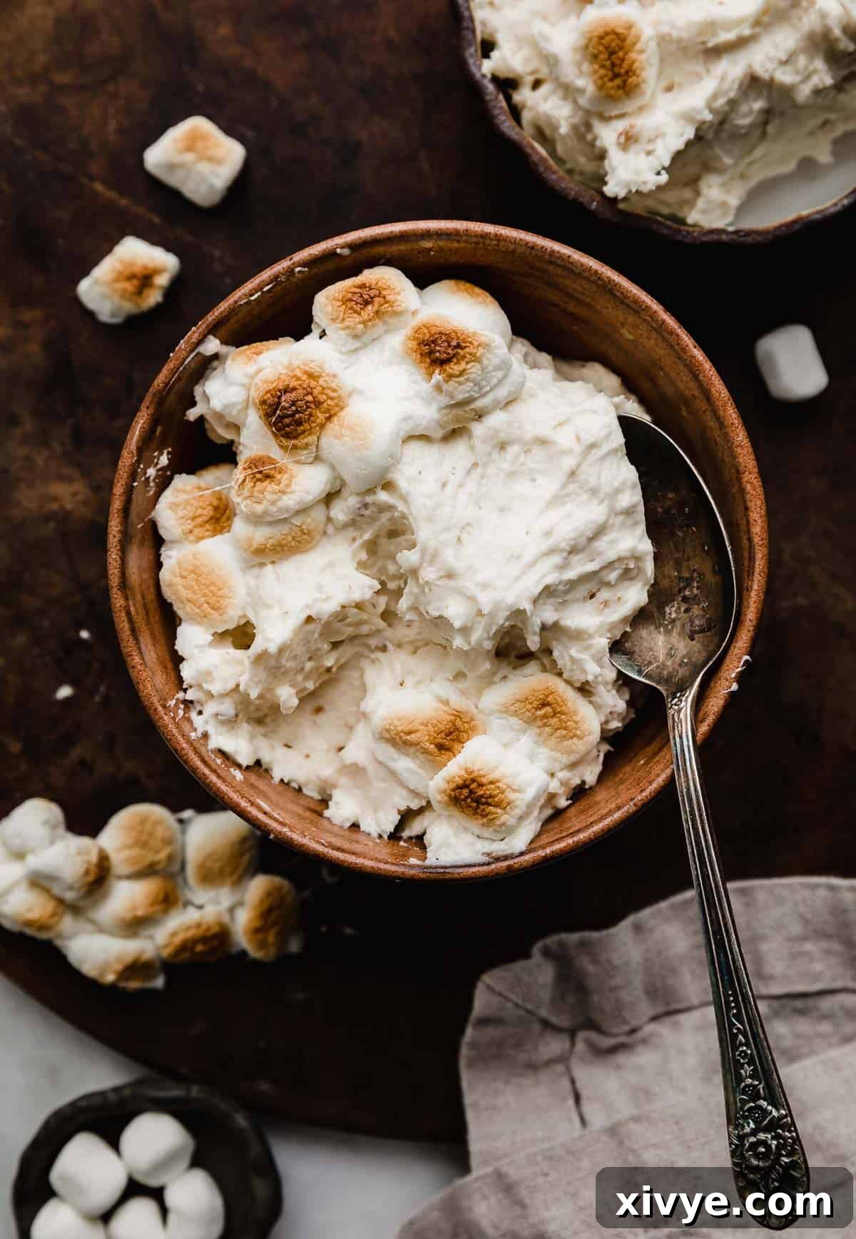 Toasted Marshmallow Frosting made with real toasted marshmallows, in a brown bowl on a dark brown surface, ready to be enjoyed.