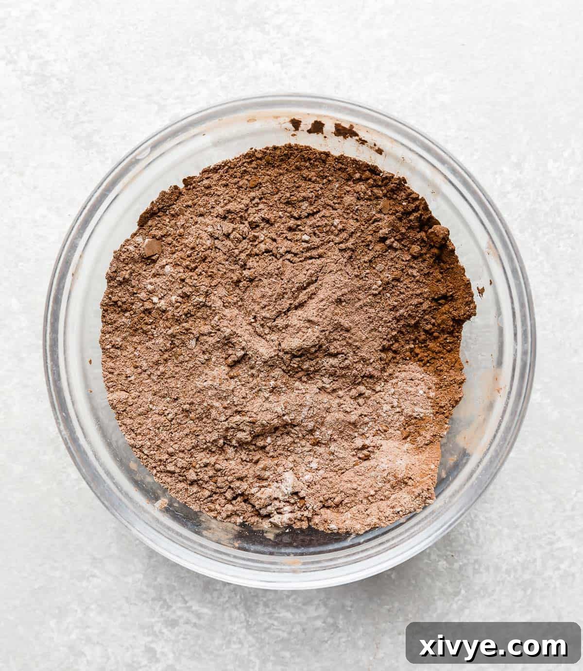 A light brown, well-combined flour mixture in a glass bowl after whisking dry ingredients.