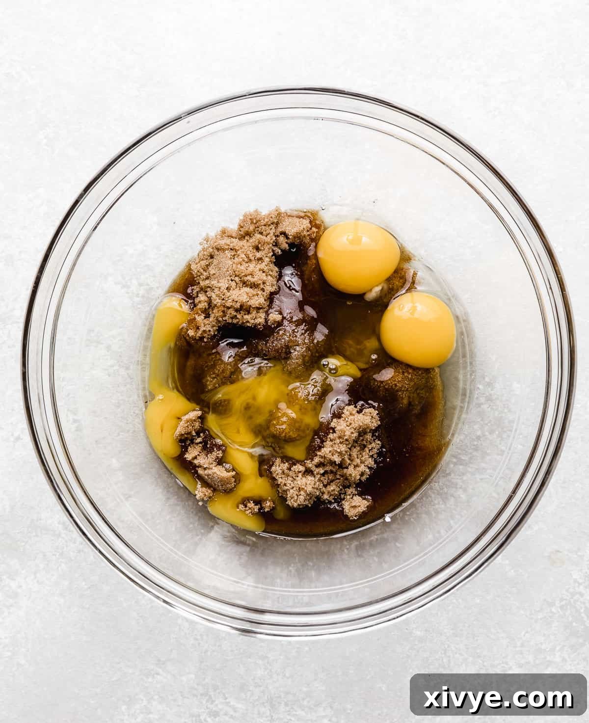 Brown sugar, cracked eggs, and vanilla extract in a glass bowl, ready to be whisked for the fudgy chocolate crinkle cookie dough.