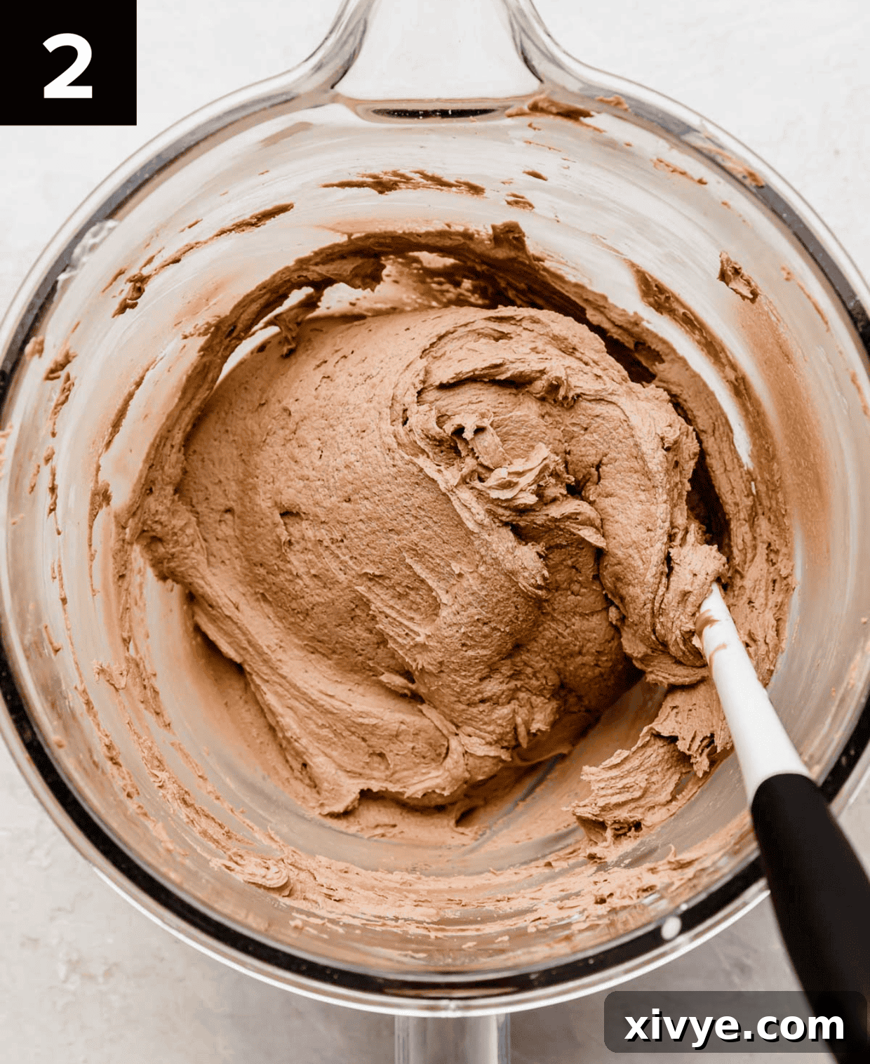 Decadent Nutella Frosting 5 Nutella buttercream frosting in a glass mixing bowl on a light gray background.