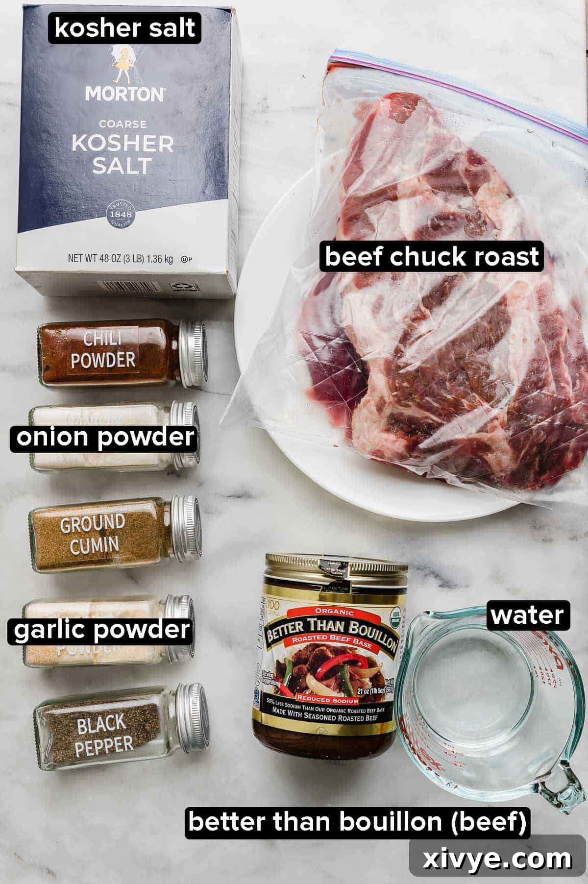 Crock Pot Shredded Beef Tacos ingredients on a marble surface: beef chuck roast, kosher salt, chili powder, onion and garlic powder, cumin, and black pepper, with water and beef bouillon.