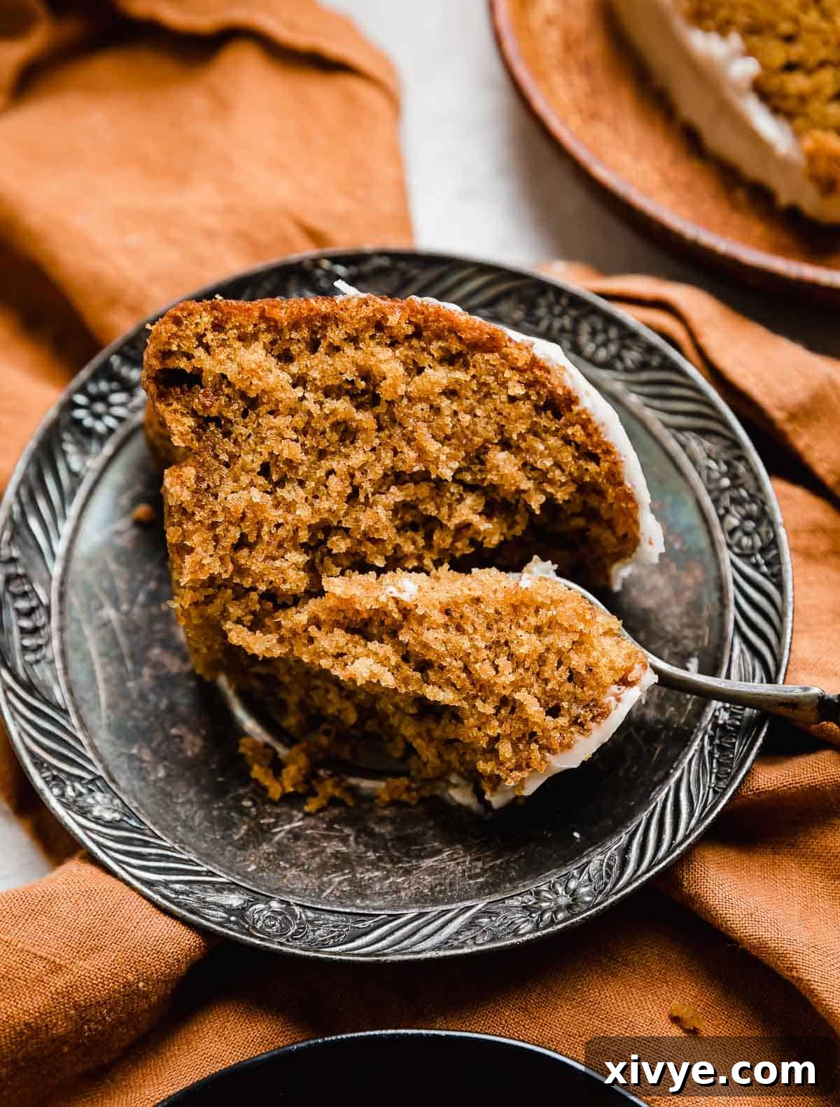 A slice of Pumpkin Bundt Cake on a vintage plate with a fork cutting into the pumpkin cake.