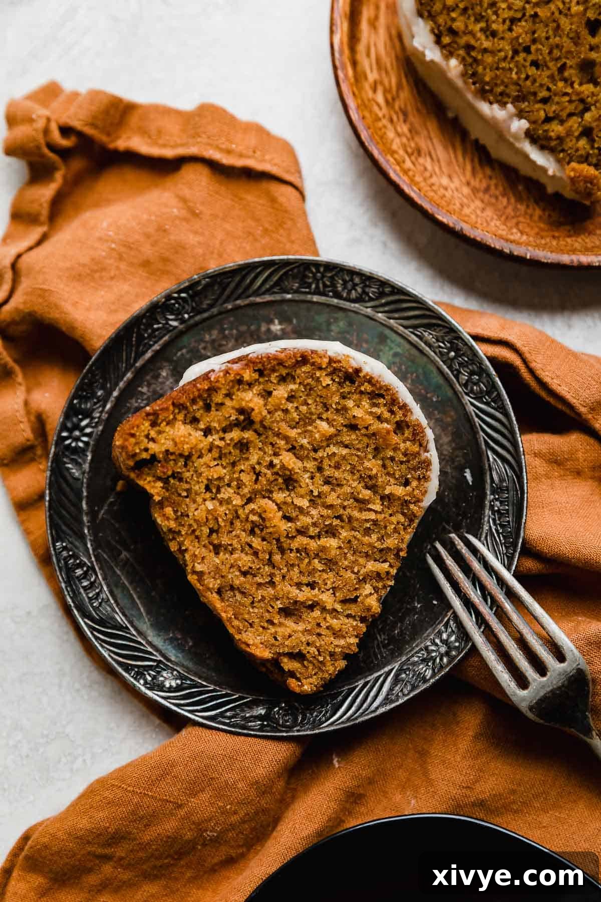 The best pumpkin bundt cake slice on a vintage plate that's on an orange linen napkin.