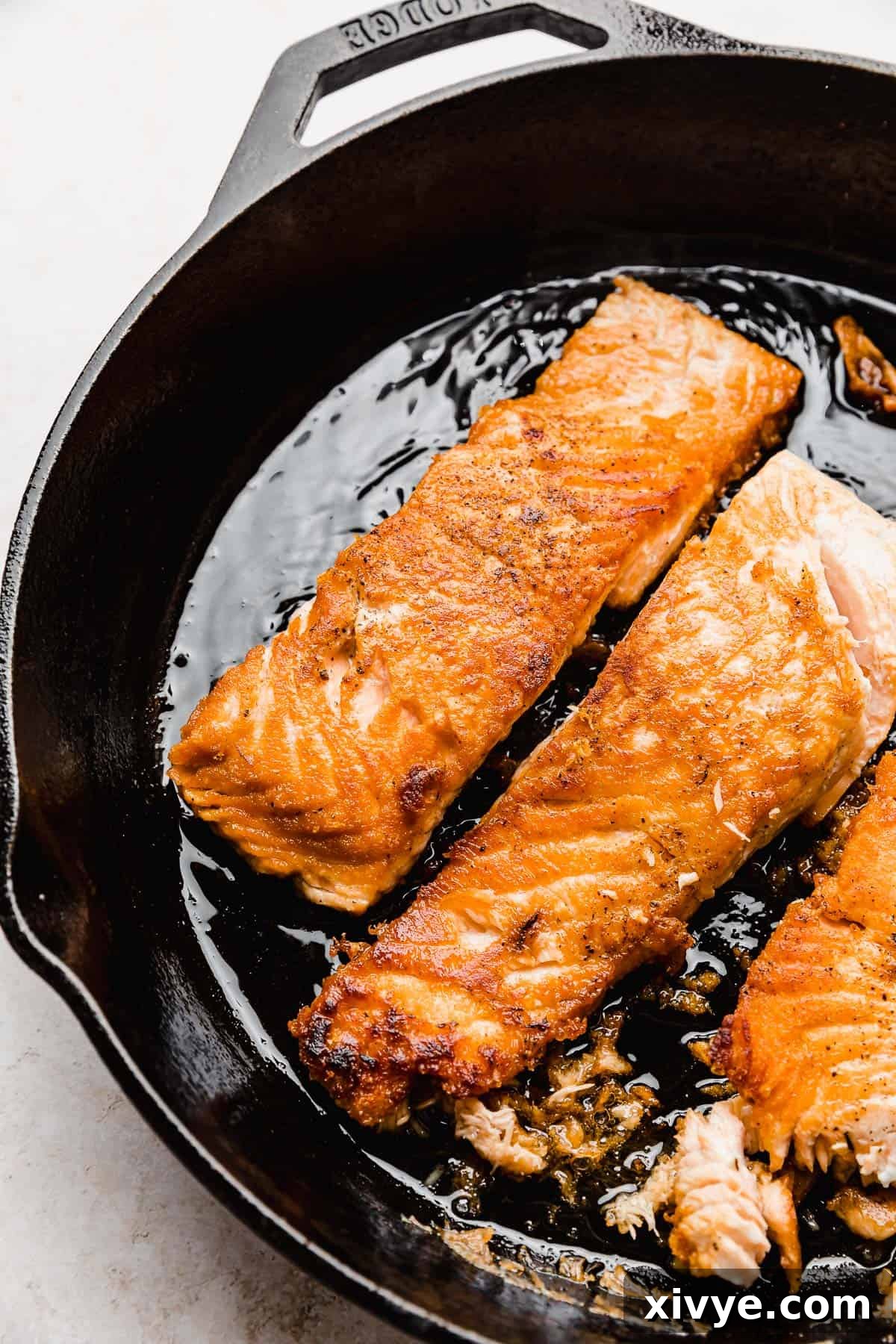 Honey-Kissed Lemon Salmon 4 Seared Lemon Honey Glazed Salmon fillets resting in a hot cast iron skillet, ready to be glazed.