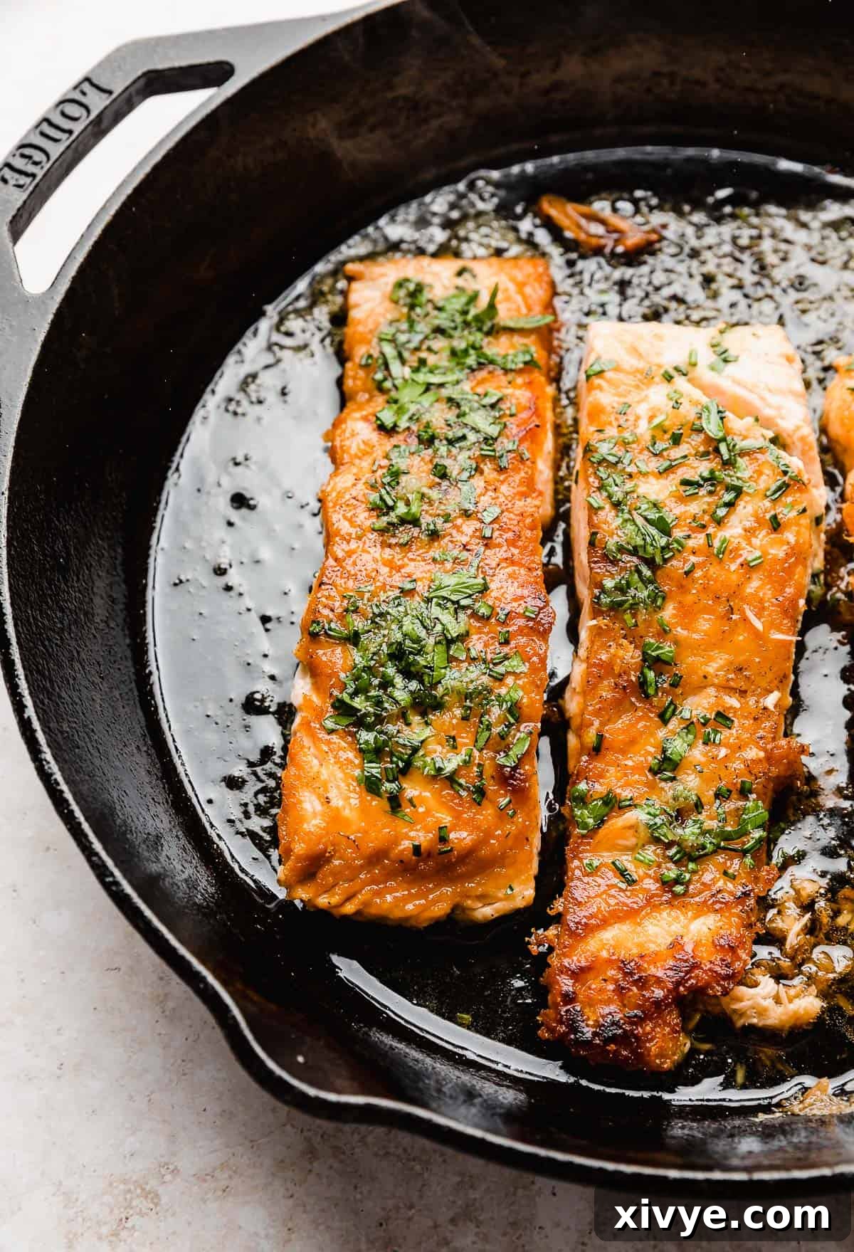 Honey-Kissed Lemon Salmon 5 A finished Lemon Honey Glazed Salmon in a black skillet, drizzled with fresh lemon honey sauce and garnished with herbs.