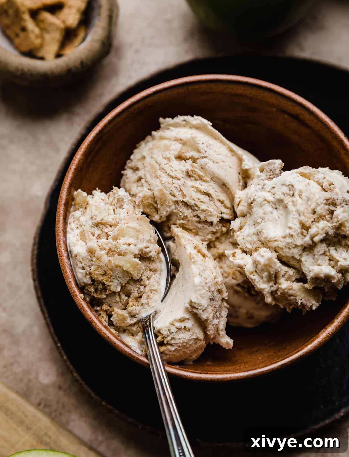 A spoon scooping out Apple Pie Ice Cream from a brown bowl.