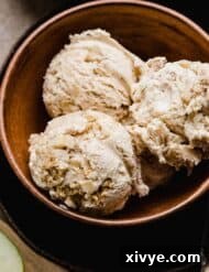 Three scoops of Apple Pie Ice Cream studded with cinnamon apples and cinnamon graham cracker pieces in a brown bowl.