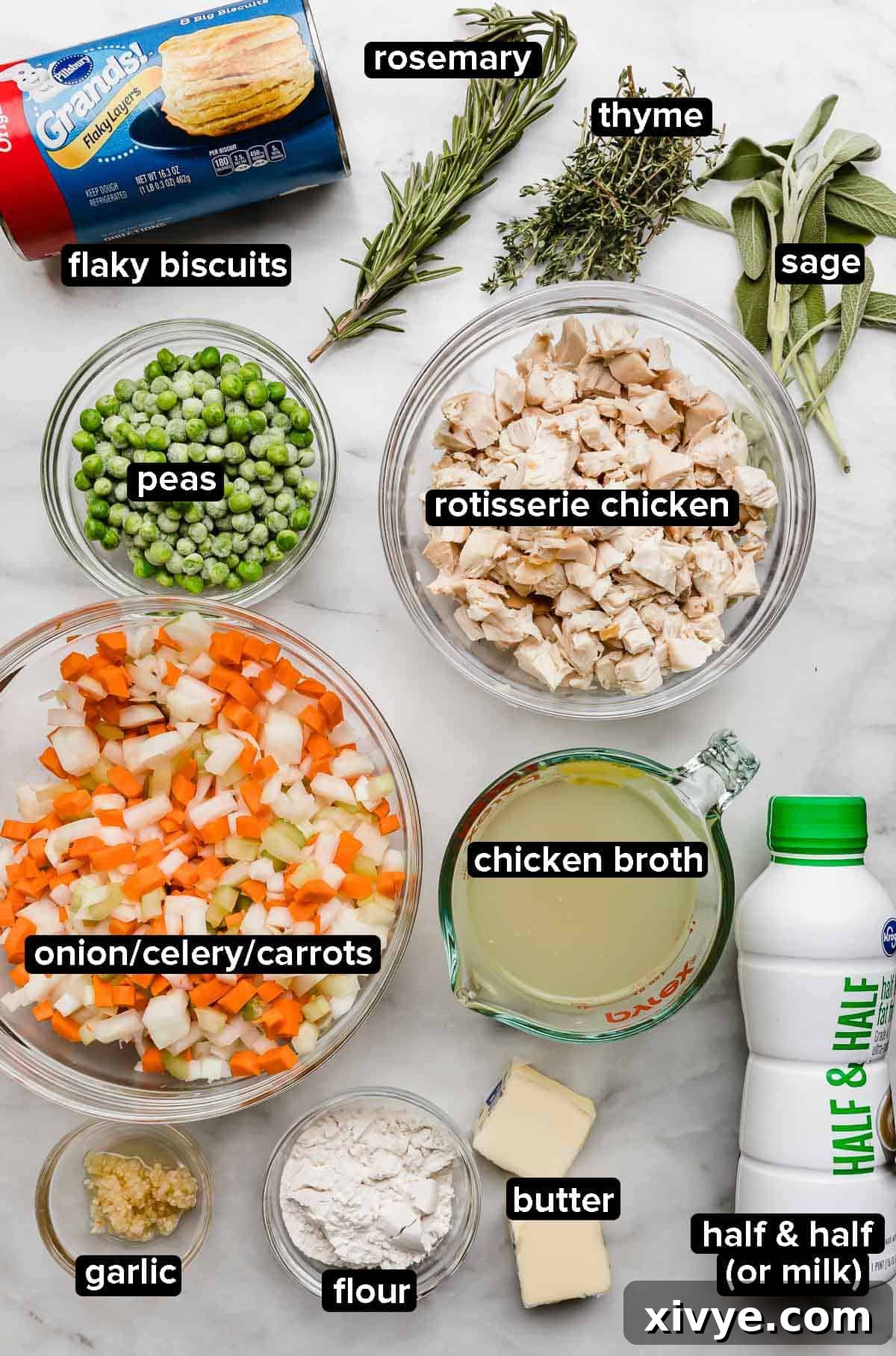 Golden-Crusted Skillet Chicken Pot Pie 3 Cast Iron Chicken Pot Pie ingredients on a white marble surface: onion, carrot, celery, rosemary, thyme, sage, butter, chicken broth, flour, peas, chicken, and milk (half and half).