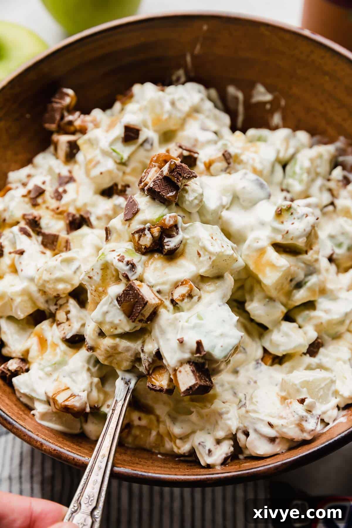 Snickers Apple Delight 6 A spoon balancing a large scoop of Apple Snickers Salad on it.
