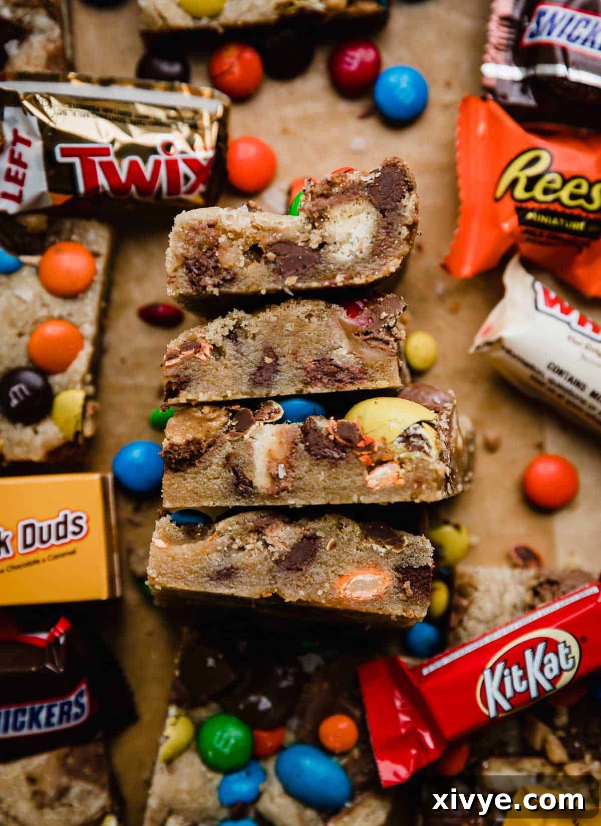 Monster Mash Candy Cookie Bars 7 Four squares of Halloween cookie bars resting on their sides, stacked against each other, showing their thick, chewy texture and candy inclusions.