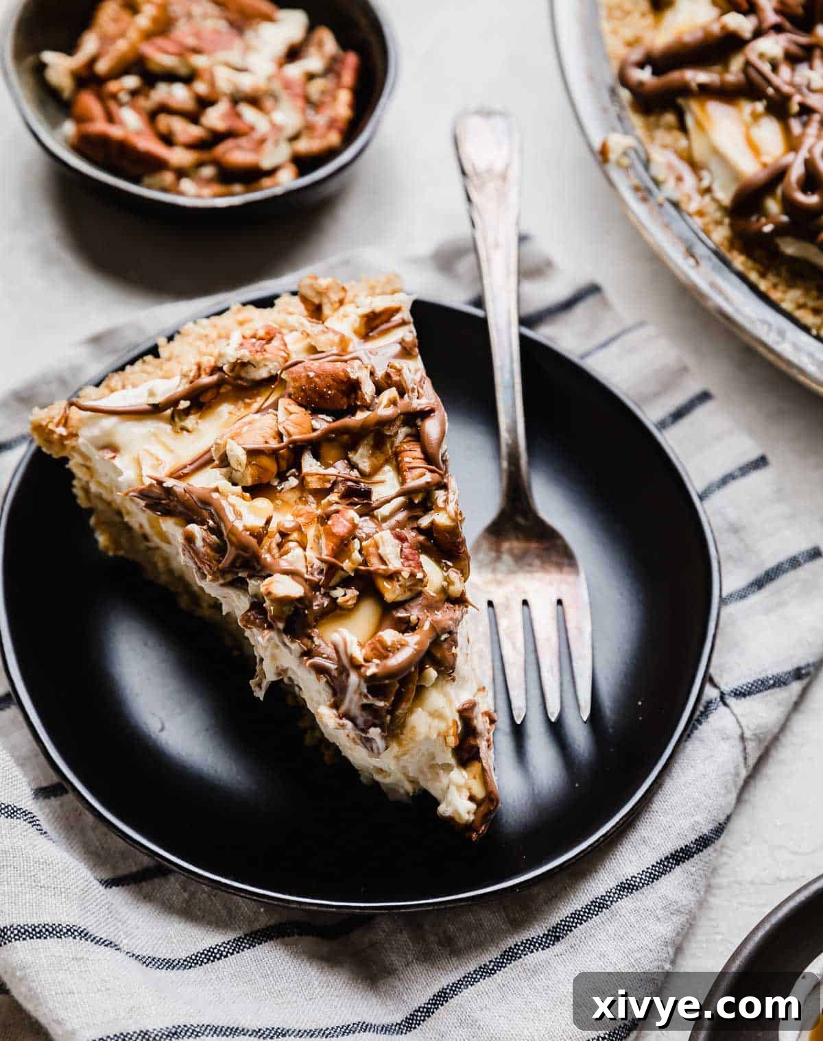 Decadent Turtle Pie 7 A slice of cream cheese caramel turtle pie on a black plate.