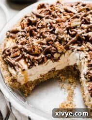 A turtle pie with a pecan crust, caramel cream cheese filling, and chocolate caramel pecan topping.