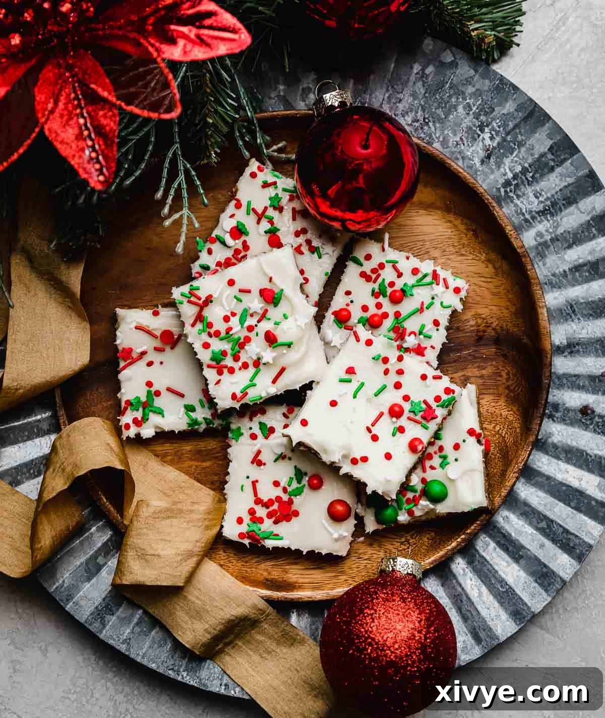 Warm Spiced Ginger Bars 7 Gingerbread Cookie Bars cut into squares, topped with cream cheese frosting and Christmas sprinkles on a brown plate.