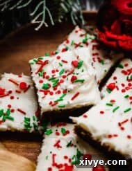 Gingerbread Cookie Bars topped with cream cheese frosting and red and green sprinkles, on a brown plate.