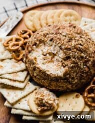 A Christmas Cheese Ball recipe on a brown plate with a portion of the cheese scooped out of the ball.