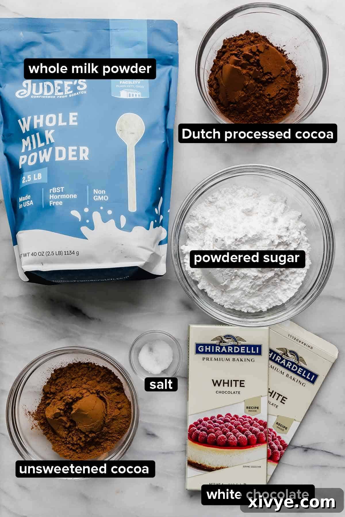 Premium Homemade Hot Chocolate Blend 3 Ingredients used to make Homemade Hot Cocoa Mix (homemade hot chocolate) on a white marble surface: whole milk powder, cocoa powders, white chocolate, salt, and powdered sugar.