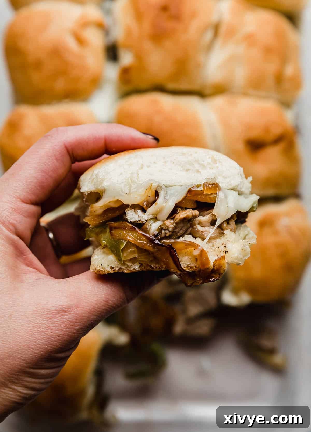 Ultimate Philly Cheesesteak Sliders 7 A hand holding the best Philly Cheesesteak Slider made on Hawaiian rolls.
