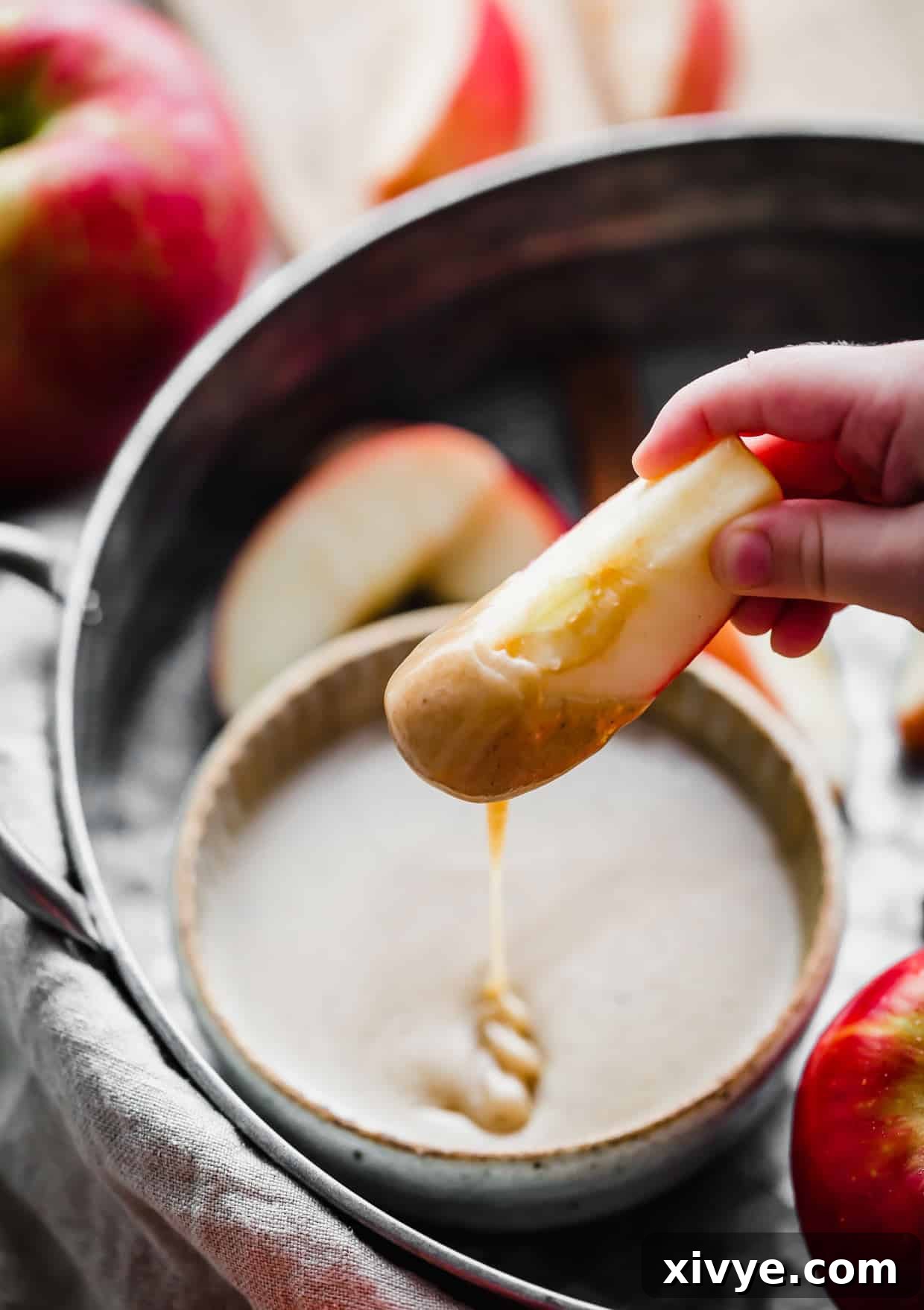 Decadent Caramel Apple Indulgence 6 An apple slice generously dipped in homemade caramel dip, showing its smooth texture.