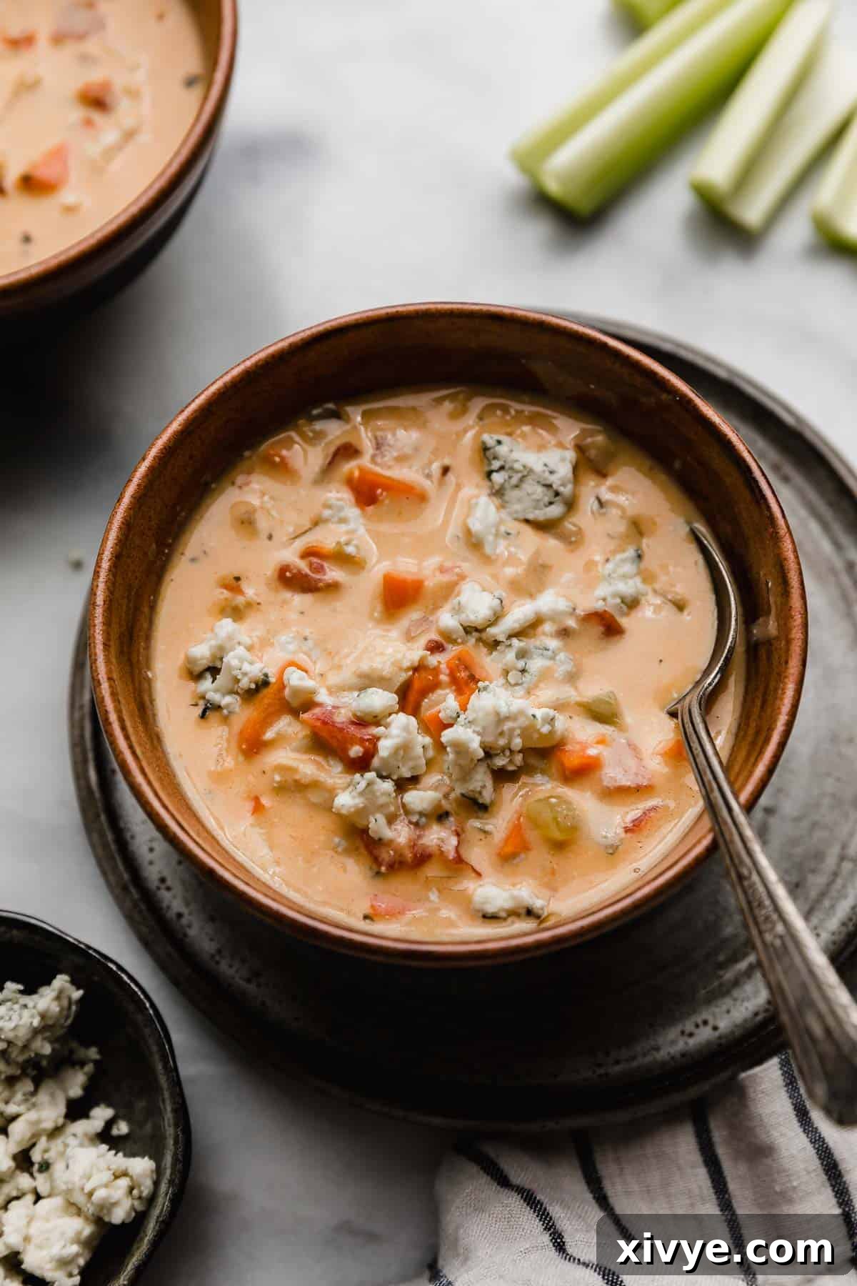 The best Buffalo Chicken Soup recipe in a brown bowl with blue cheese crumbles overtop.