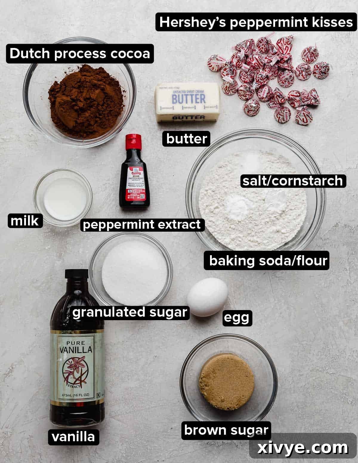 Chocolate Peppermint Blossom cookies ingredients on a light gray background: cocoa, sugars, egg, butter, Hershey's kisses, and peppermint extract.