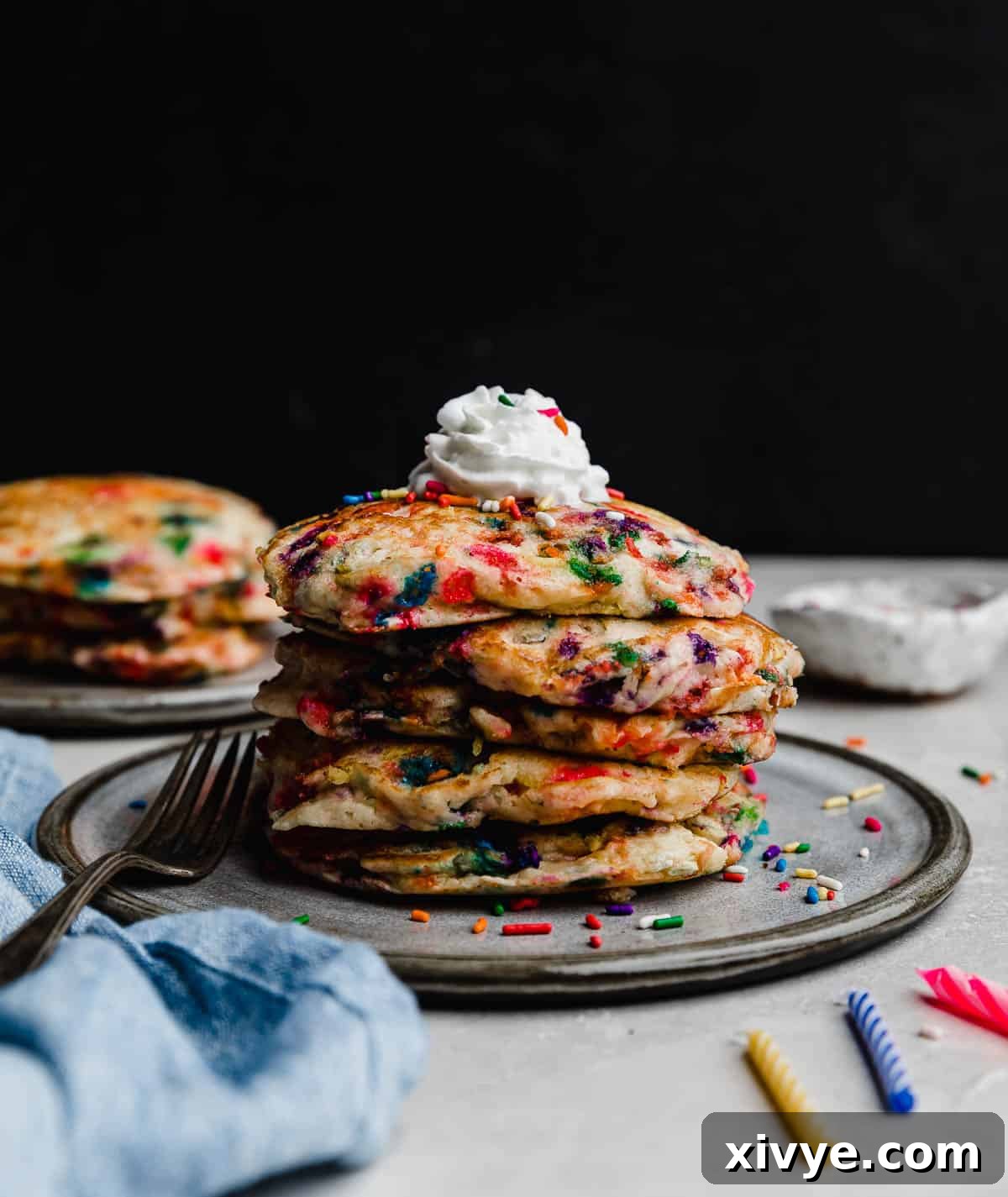 A stack of Birthday Cake Pancakes (funfetti pancakes) on a gray plate against a black background.