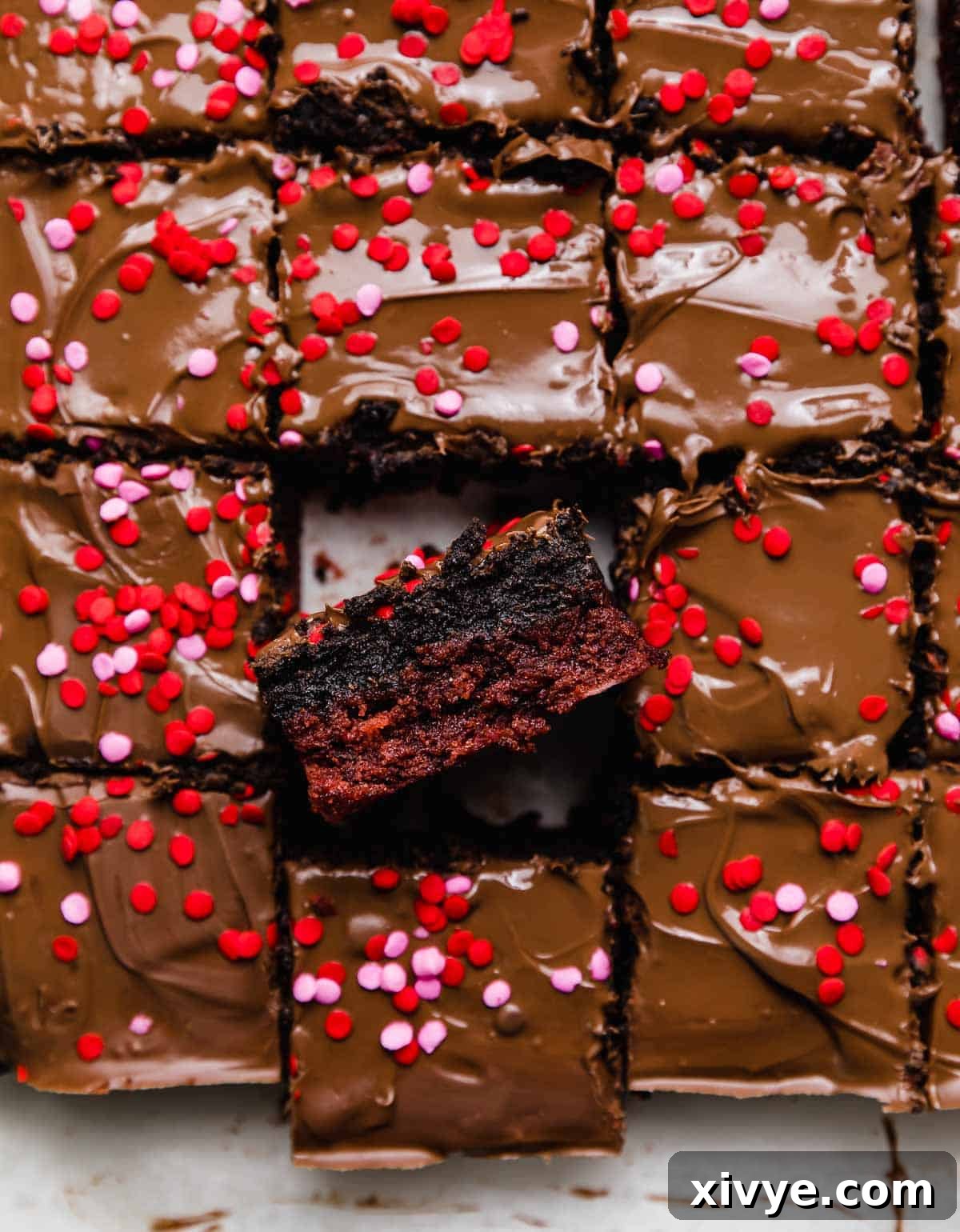Decadent Red Velvet Oreo Truffle Brownies 2 Red Velvet Oreo Brownies topped with melted milk chocolate and pink and red sprinkles, cut into squares.