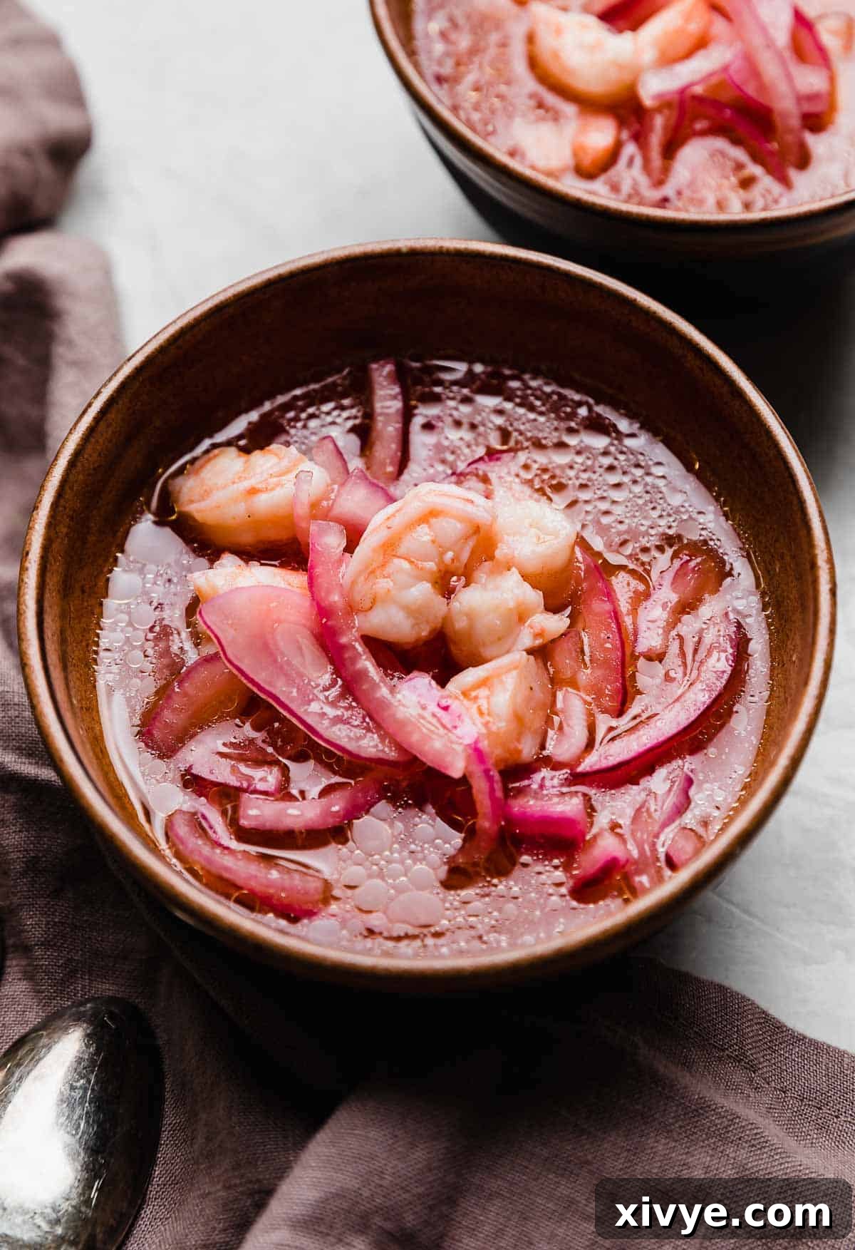 Effortless Cooked Shrimp Ceviche 2 Shrimp Ceviche with thinly sliced red onion in a vibrant lemon and lime juice mixture, garnished for serving.