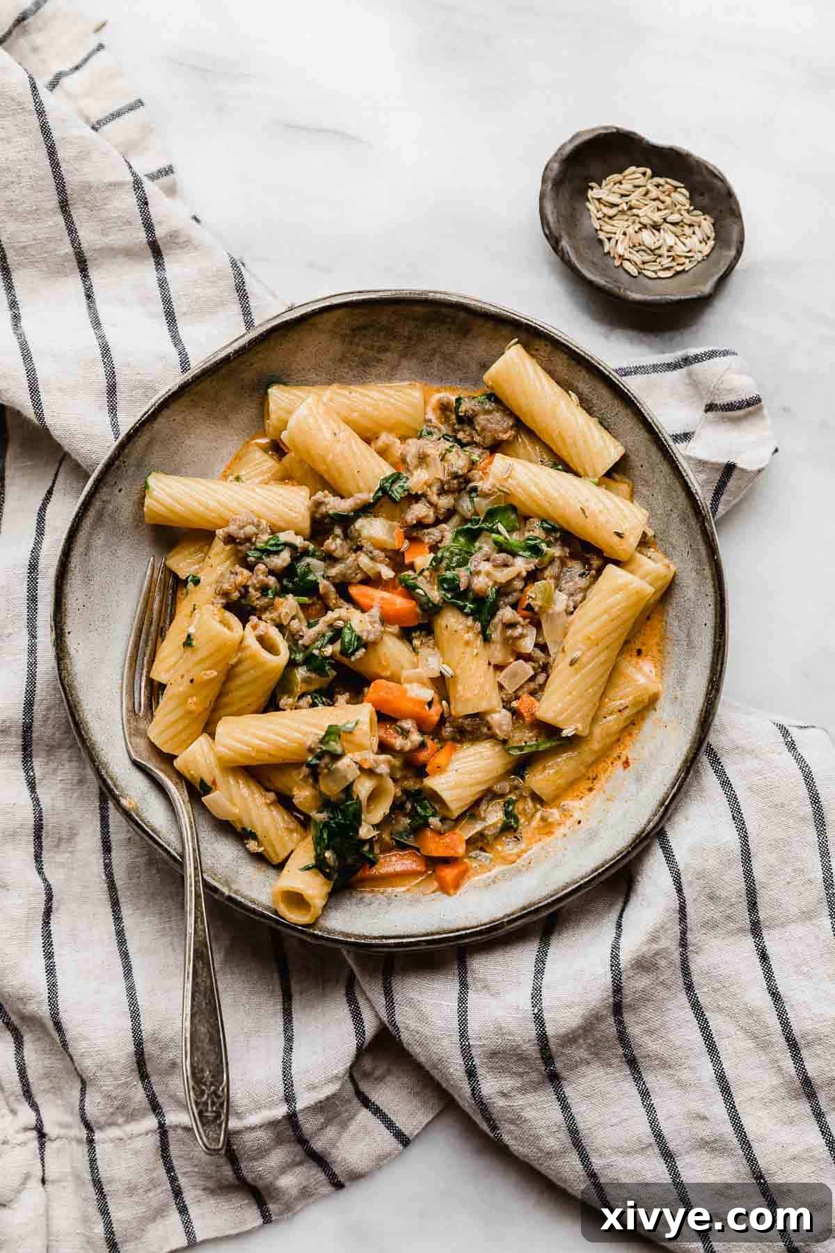 Hearty Italian Sausage Rigatoni 7 A gray pasta plate topped with the best Sausage and Rigatoni pasta recipe with carrots and spinach.