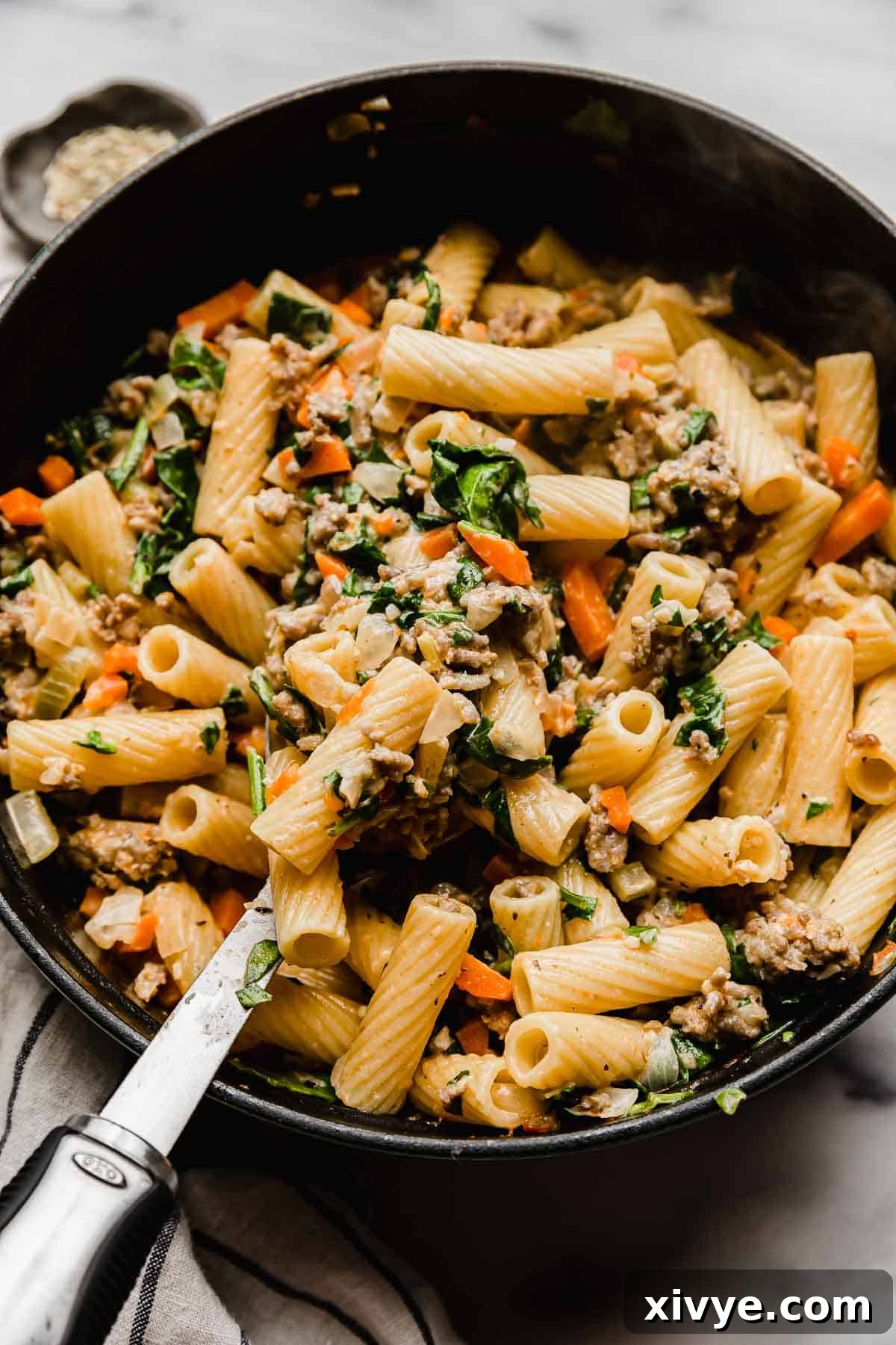 Hearty Italian Sausage Rigatoni 8 A serving spoon scooping up a portion of homemade Italian Sausage Rigatoni from a large pot.