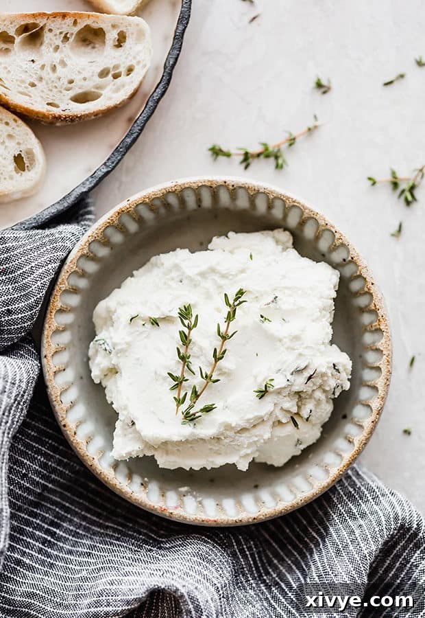 Sweet Caramelized Onion and Tangy Goat Cheese Crostini 4 A bowl of whipped goat cheese and cream cheese with a sprig of fresh thyme overtop.
