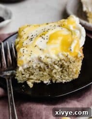 A slice of moist lemon poppy seed sheet cake on a black plate.