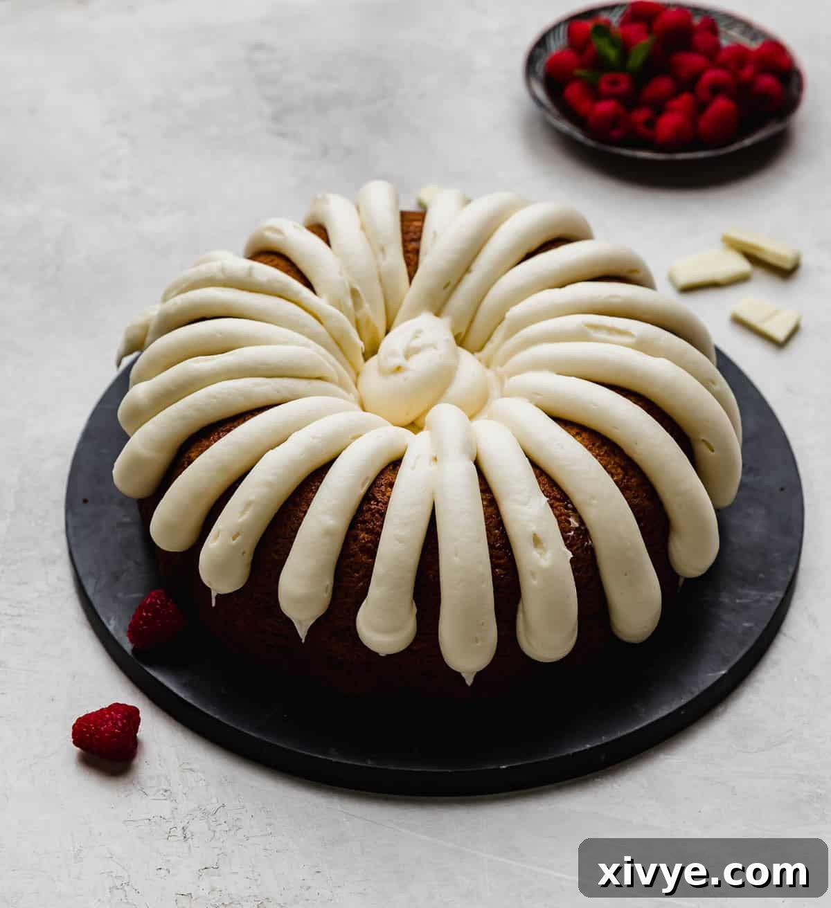 A Nothing Bundt Cake White Chocolate Raspberry Bundt Cake copycat recipe on a black plate on a light gray background. 