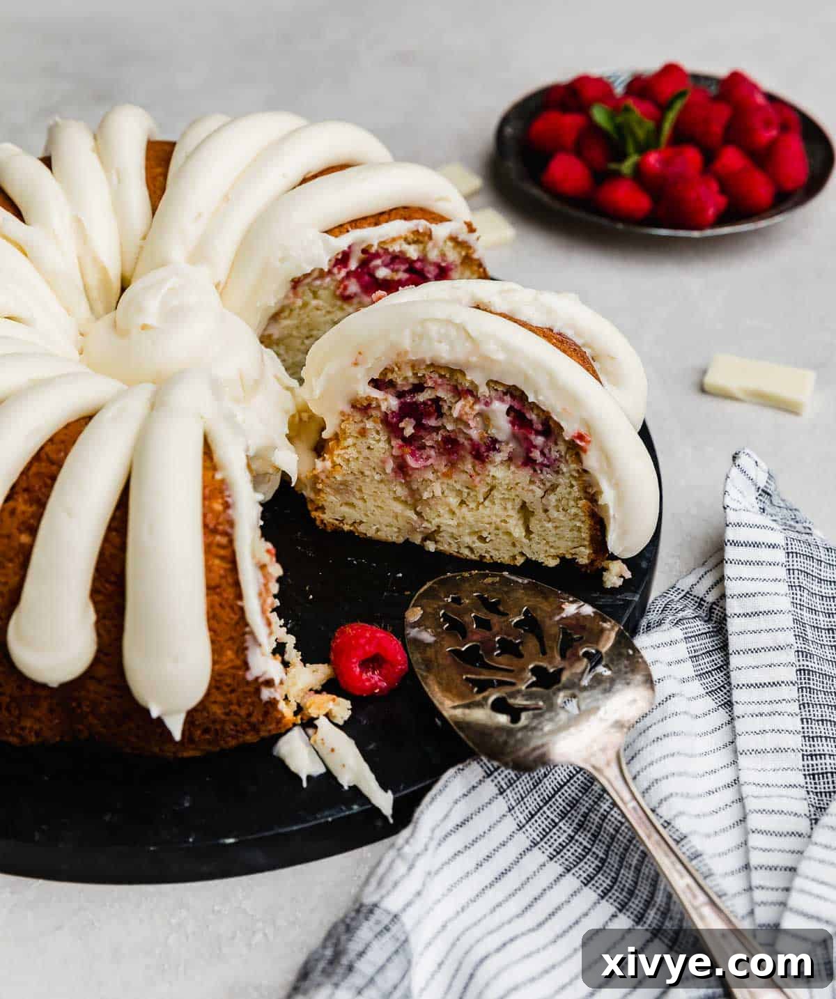 A White Chocolate Raspberry Bundt Cake recipe with a few slices removed from the cake.