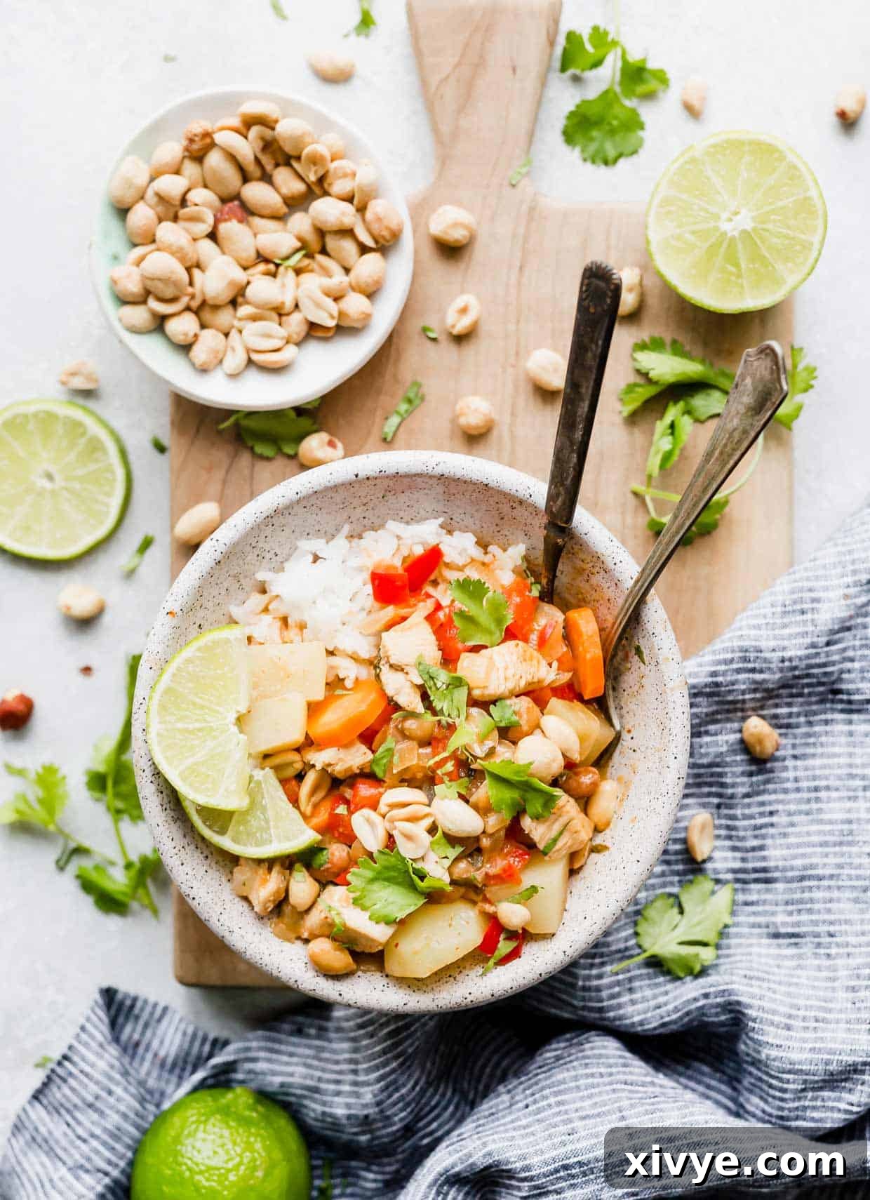 A bowl with an easy Massaman Curry topped with lime, cilantro, and peanuts.