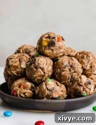 Monster Cookie Protein Balls with protein powder and M&M's on a black plate against a white background.