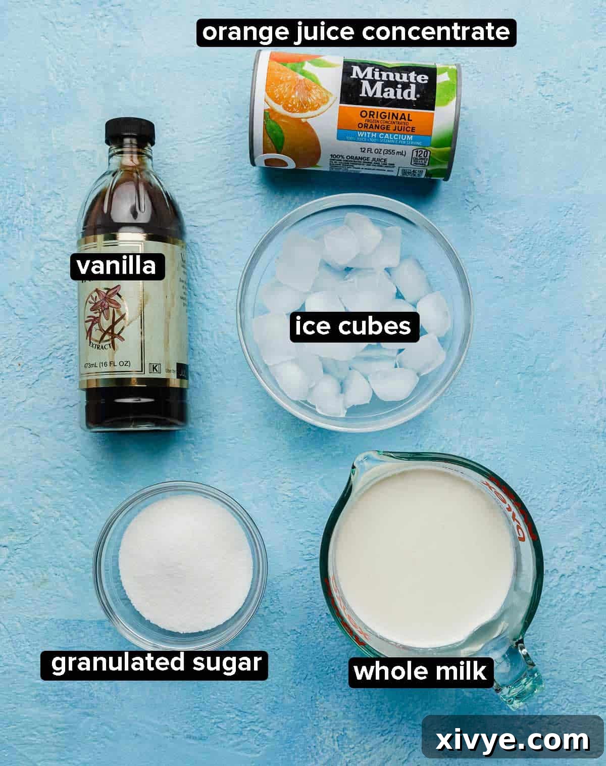 Orange Julius Recipe ingredients on a bright blue background: vanilla, orange juice concentrate, ice cubes, milk, and sugar.