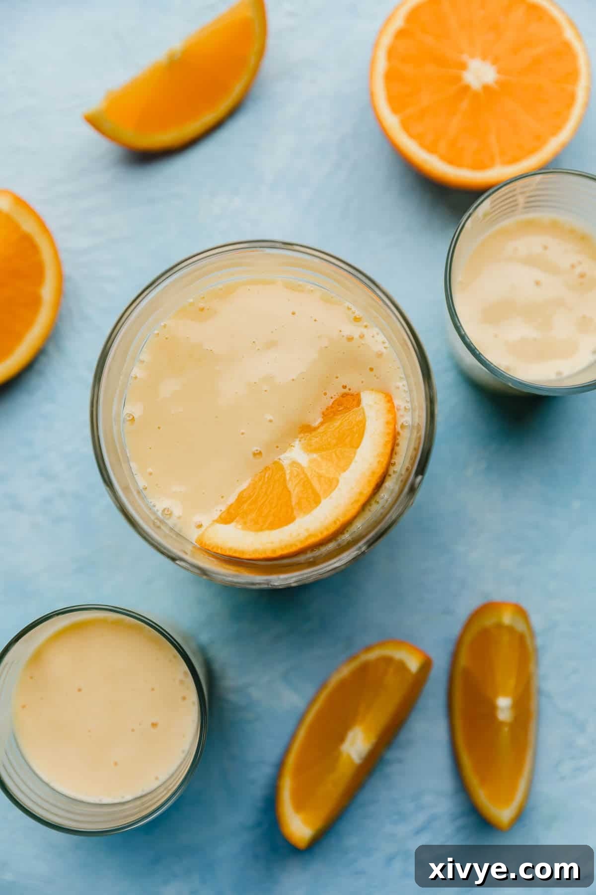 Overhead photo of 3 glass cups filled with an Orange Julius drink.
