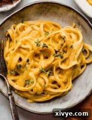 Alfredo butternut squash pasta in a gray pasta bowl topped with fresh thyme.