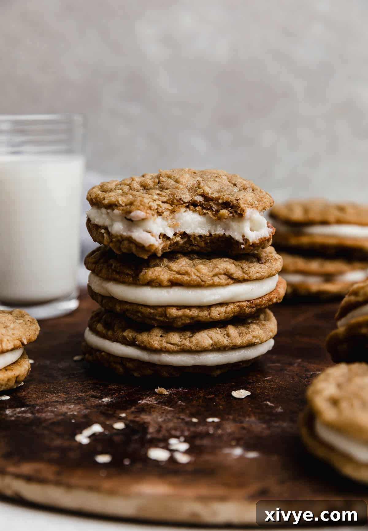 Three oatmeal creme pie cookies stacked, with the top cookie having a perfect bite removed from it, revealing the creamy filling.