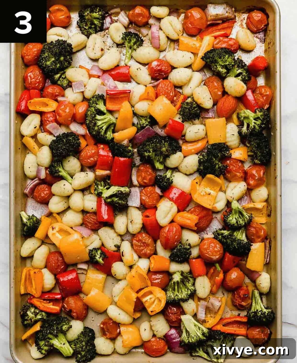 A baking sheet filled with beautifully roasted gnocchi and a variety of colorful vegetables, cooked to tender-crisp perfection and ready to be served.