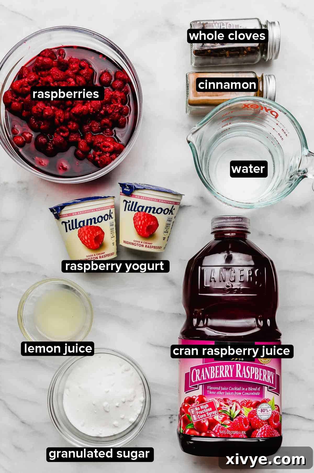 Ingredients used to make Cold Raspberry Soup recipe: cranberry raspberry juice, sugar, lemon juice, raspberry yogurt, fresh raspberries, cinnamon, cloves, and water, laid out on a marble counter.