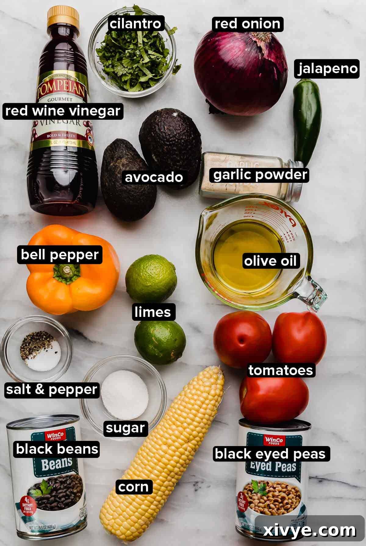 Vibrant Tex Mex Fiesta Salad 3 Texas Caviar ingredients on a white marble surface: bell pepper, tomatoes, corn, beans, avocado, cilantro, jalapeño, red wine vinegar, salt and pepper.
