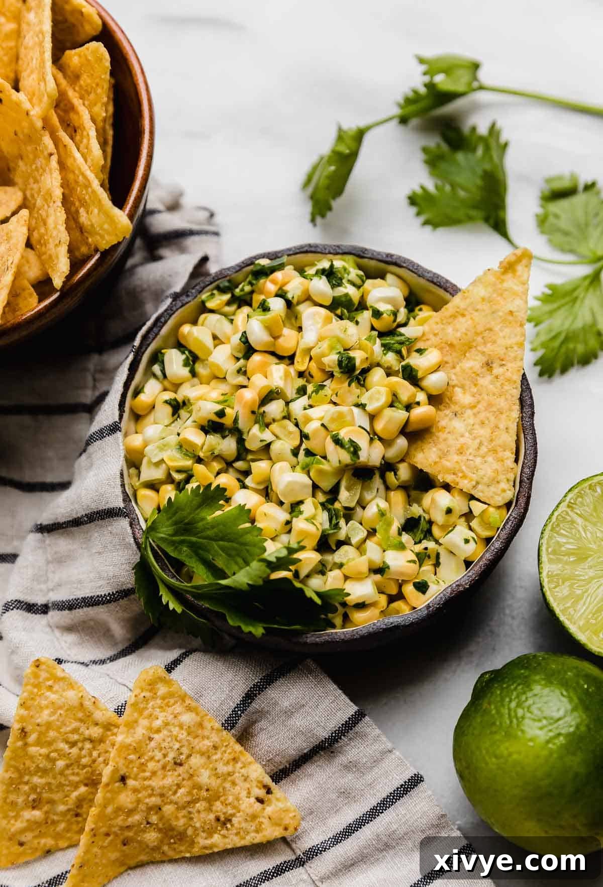 A black bowl filled with Fresh Corn Salsa with jalapeño and cilantro on a white background.